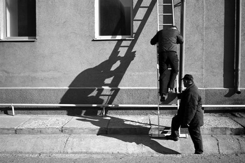 black and white image of men on ladder