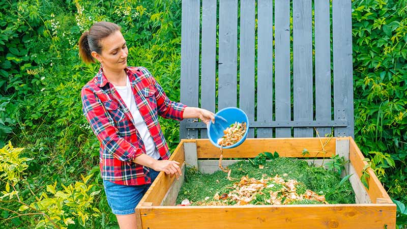 Woman adding food waste to garden compost