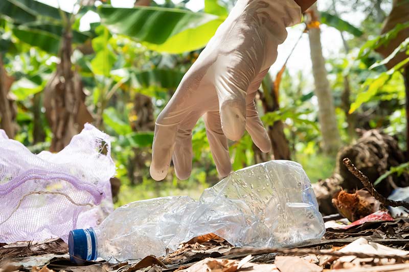 Discarded plastic bottle being collected off the ground outside by a litter picker