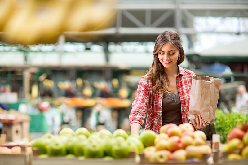 Woman shopping for fruit using a brown paper bag