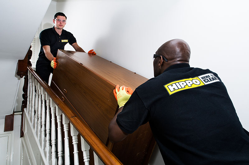 Man and van team taking a wardrobe down a stairs in a house