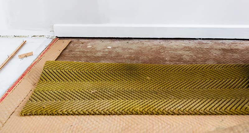 Old carpet underlay being removed from a room