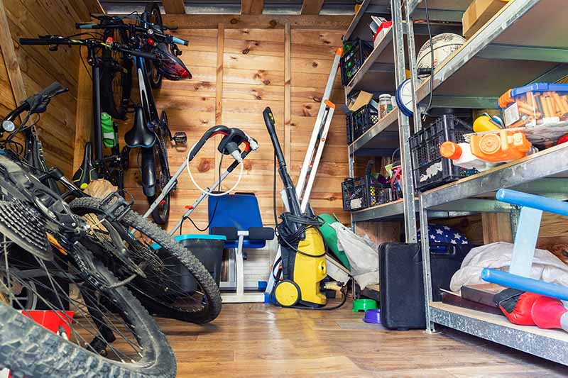 A shed with many items stored on the floor and on metal rack shelves