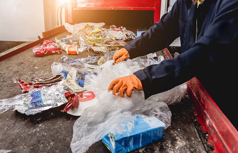 Recycling plant worker sorting waste on a conveyor belt