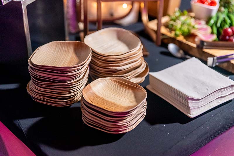 3 stacks of palm leaf disposable plates on a table for a gathering