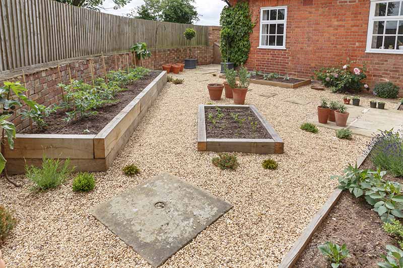 Raised garden made from oak sleepers in a gravelled garden