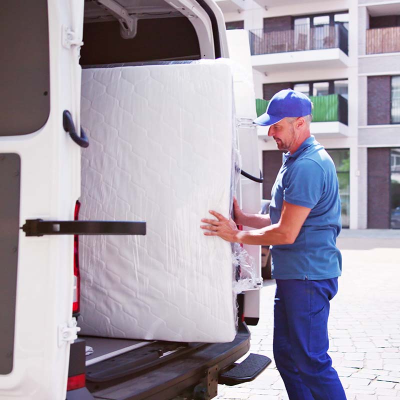 Person loading a mattress into the back of a van