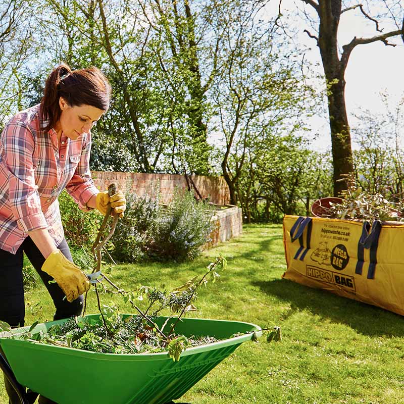 Woman disposing of garden waste with a HIPPOBAG in the background