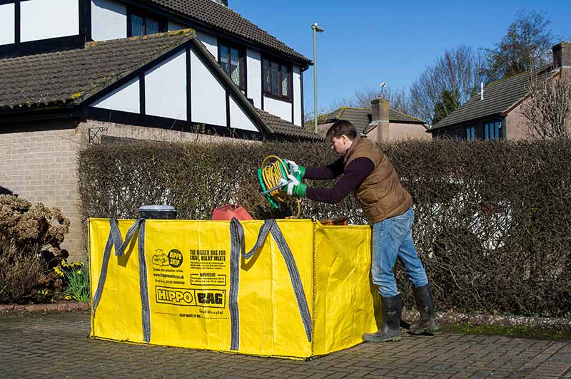 A man filling our largest HIPPOBAG, a HIPPOSKIP, on a driveway